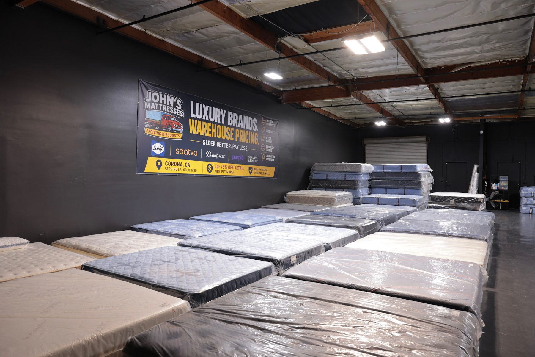 Rows of wrapped mattresses on the warehouse floor with stacked inventory behind